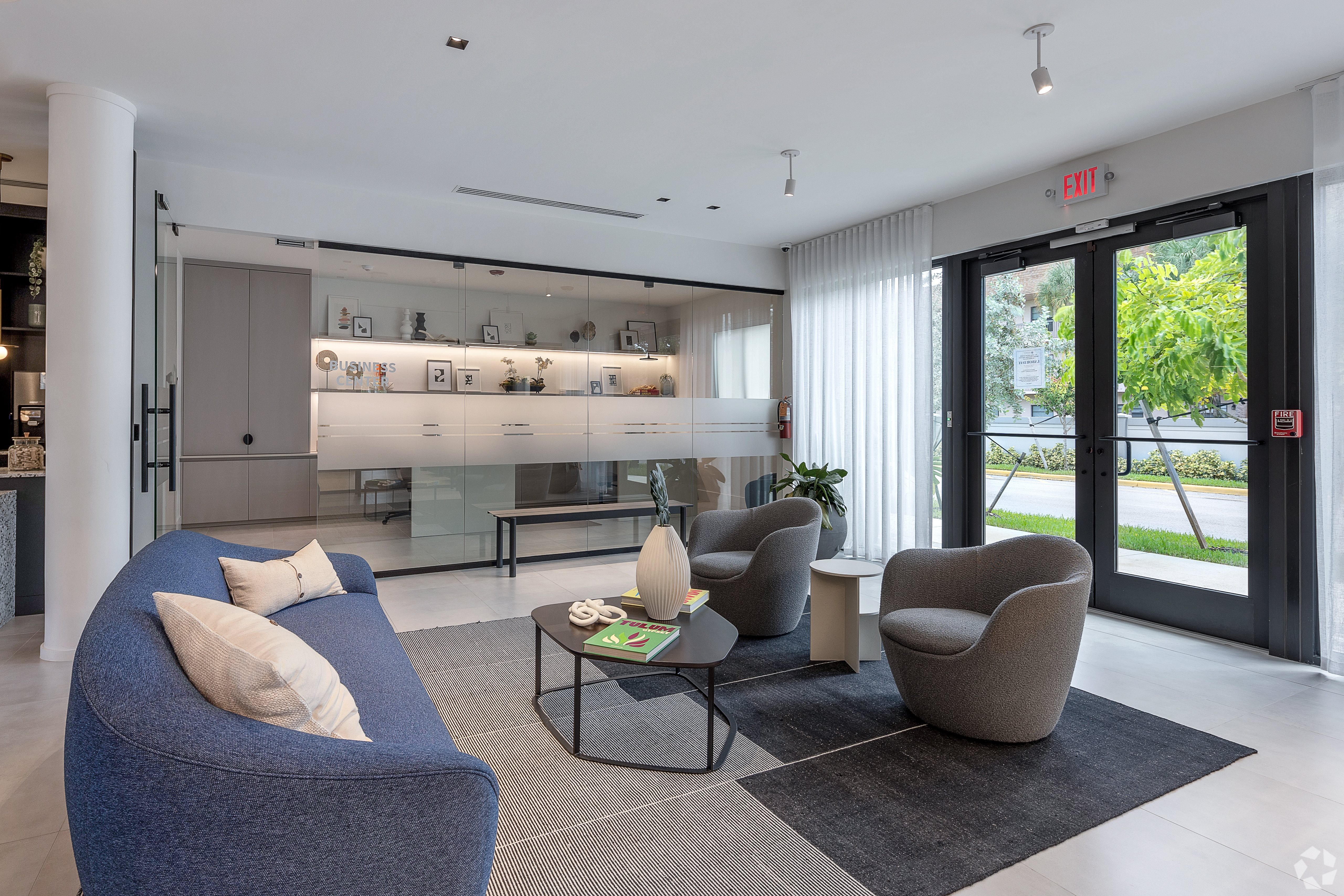 A modern living room with a blue sofa and a glass wall.
